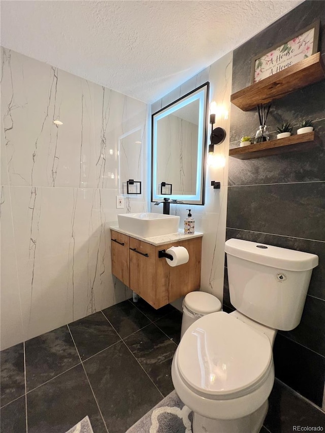 bathroom with vanity, tile walls, toilet, and a textured ceiling