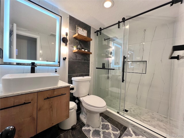 bathroom featuring toilet, tile walls, a shower with door, vanity, and a textured ceiling