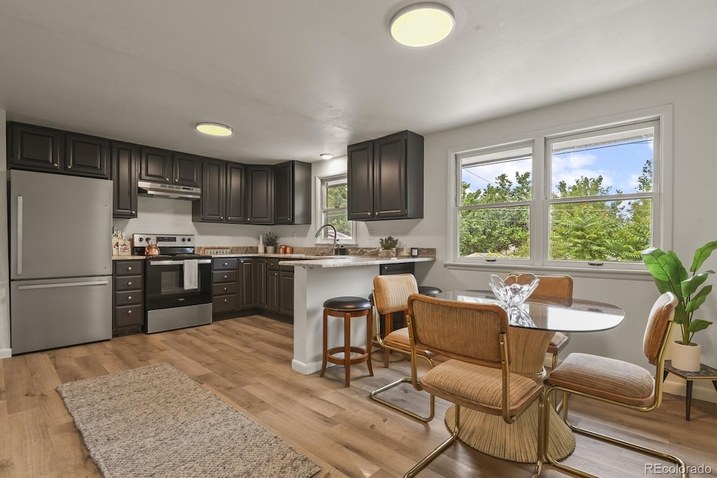 kitchen featuring plenty of natural light, a kitchen breakfast bar, stainless steel appliances, and light hardwood / wood-style flooring