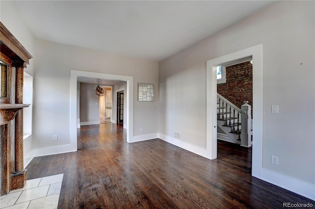 unfurnished living room featuring hardwood / wood-style flooring and brick wall