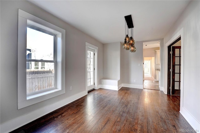 spare room featuring an inviting chandelier and dark wood-type flooring