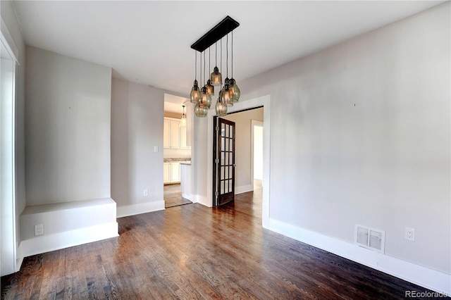 spare room featuring dark hardwood / wood-style flooring and a chandelier