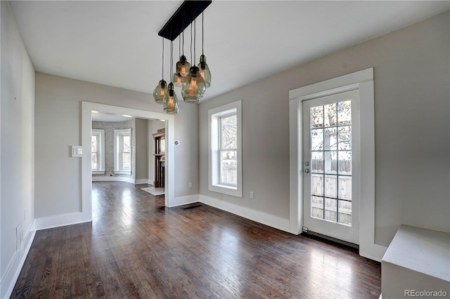 unfurnished dining area featuring dark hardwood / wood-style flooring, a wealth of natural light, and a chandelier