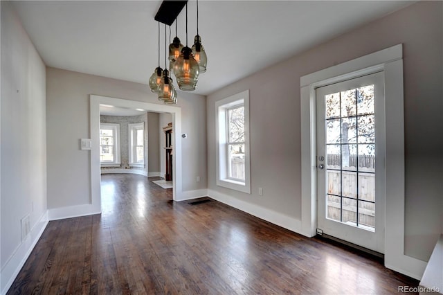 unfurnished dining area featuring a chandelier, dark hardwood / wood-style flooring, and a wealth of natural light