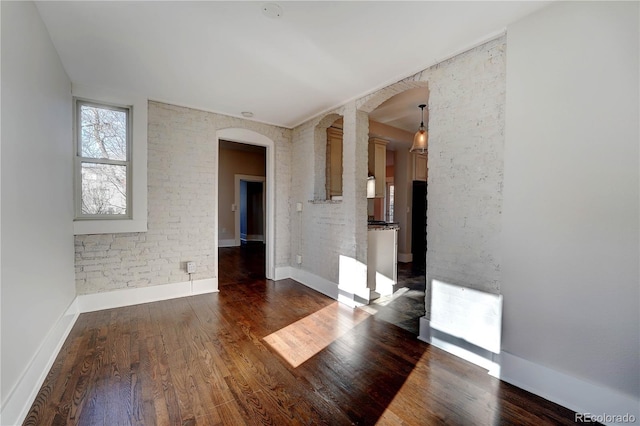 spare room featuring brick wall and dark hardwood / wood-style floors