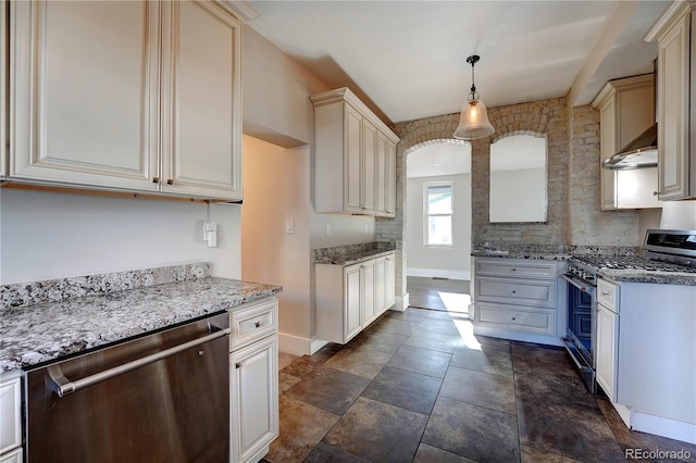 kitchen with light stone counters, stainless steel appliances, extractor fan, cream cabinets, and decorative light fixtures