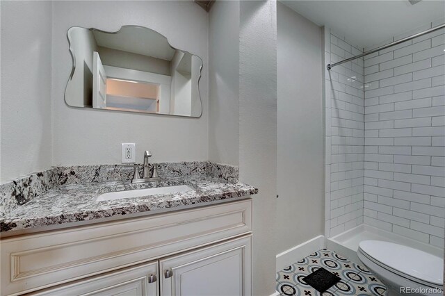 bathroom with vanity, toilet, and tiled shower