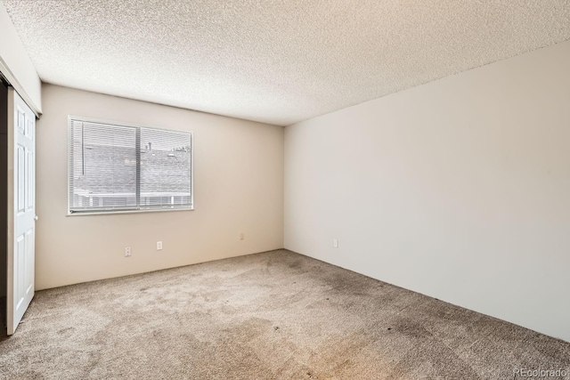 carpeted empty room with a textured ceiling