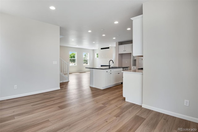 kitchen featuring a kitchen island, sink, white cabinets, and light hardwood / wood-style floors