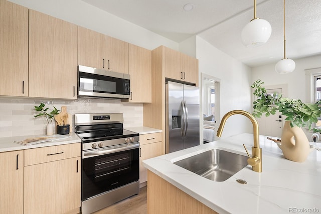 kitchen featuring stainless steel appliances, light brown cabinets, hanging light fixtures, and a sink