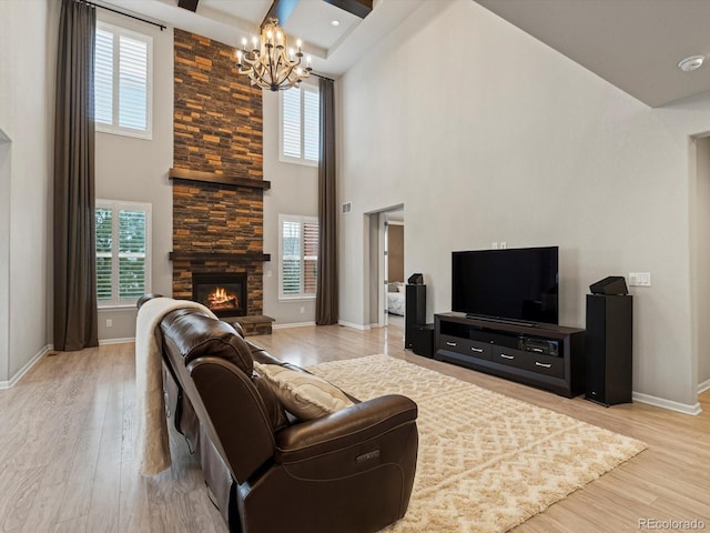 living area with light wood-type flooring, a fireplace, an inviting chandelier, and baseboards