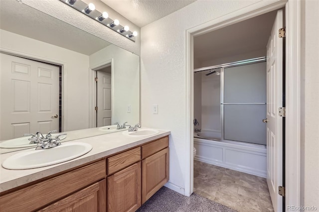 3375 Boulder Cir Unit 204, Broomfield, CO 80023 - full bath featuring double vanity, toilet, combined bath / shower with glass door, and a textured ceiling