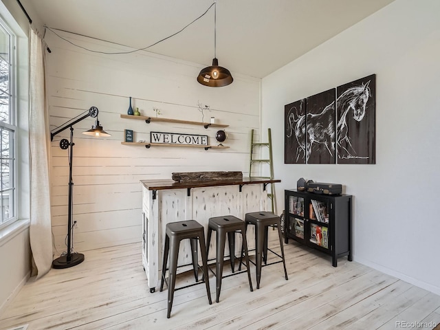 bar featuring wooden counters, wooden walls, and light hardwood / wood-style floors