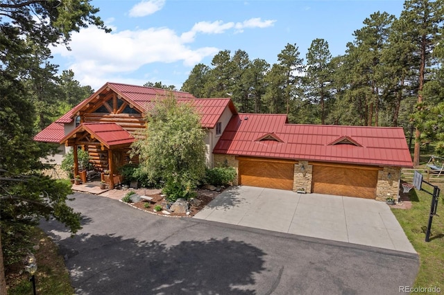 23076 Oehlmann Park Rd, Conifer, CO 80433 - view of front of house featuring a standing seam roof, a metal roof, stone siding, and concrete driveway
