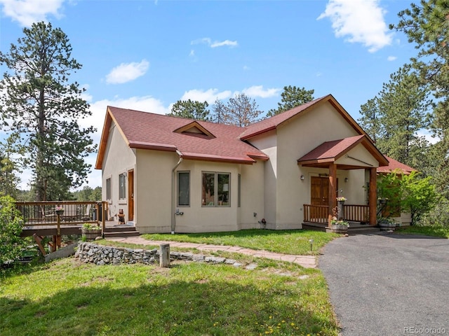 23076 Oehlmann Park Rd, Conifer, CO 80433 - view of front of house with stucco siding, a front yard, a deck, and roof with shingles
