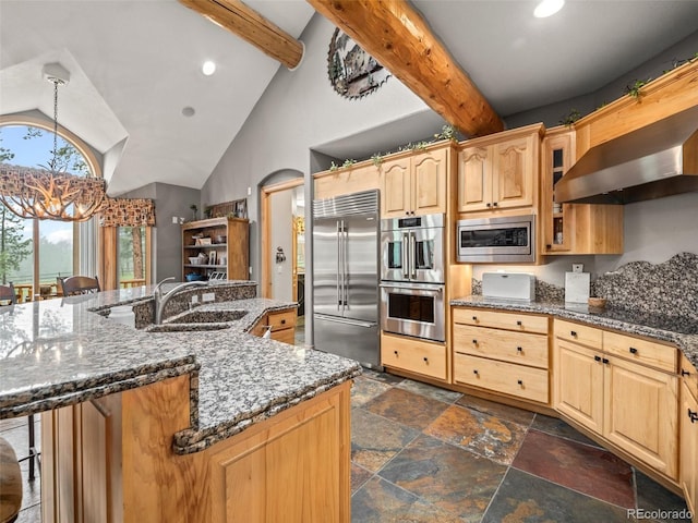 23076 Oehlmann Park Rd, Conifer, CO 80433 - kitchen with built in appliances, wall chimney range hood, stone tile floors, a breakfast bar area, and dark stone counters