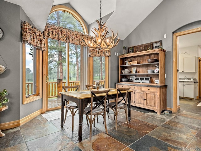 23076 Oehlmann Park Rd, Conifer, CO 80433 - dining room with vaulted ceiling, stone tile flooring, and a chandelier