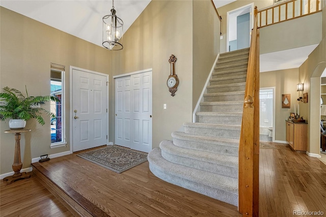 foyer entrance with high vaulted ceiling, baseboards, and hardwood / wood-style floors