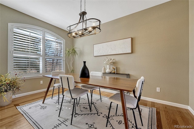 dining space with baseboards, a chandelier, and wood finished floors