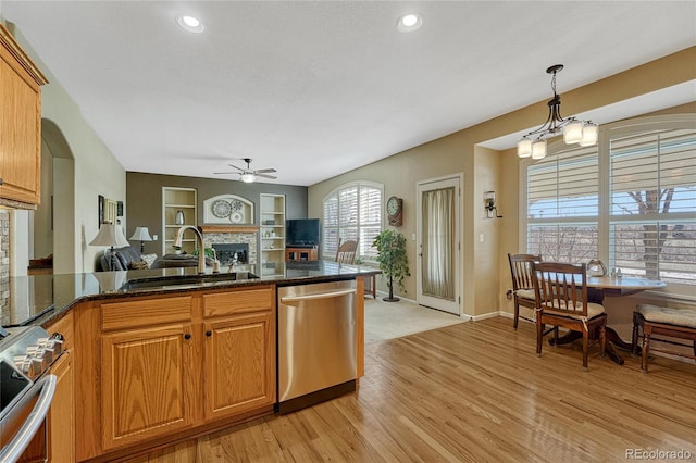 kitchen with light wood-style flooring, stainless steel appliances, a fireplace, a sink, and open floor plan