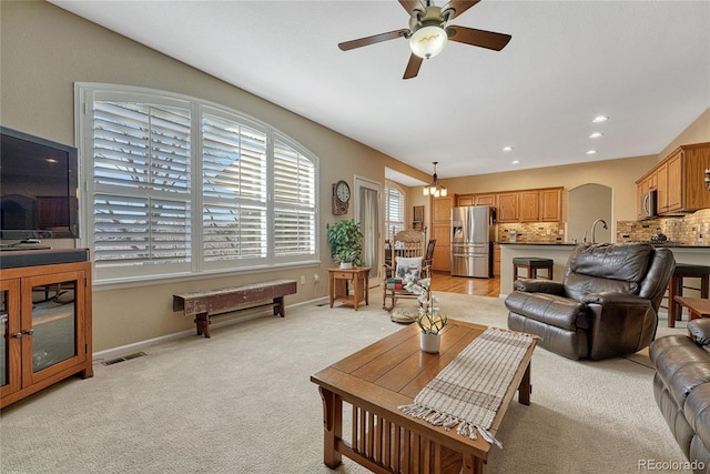 living room featuring arched walkways, recessed lighting, visible vents, light carpet, and baseboards