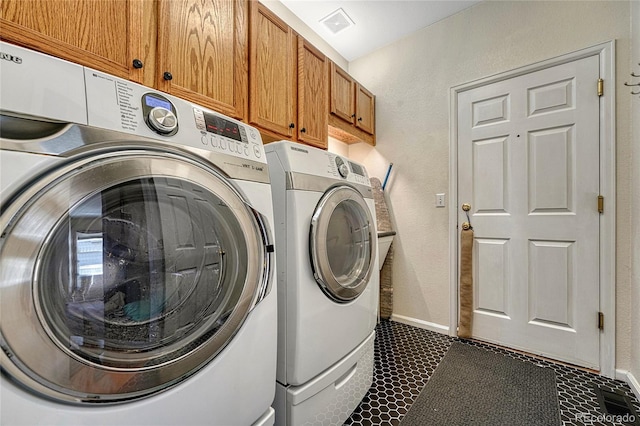 washroom with cabinet space, washing machine and dryer, baseboards, and dark tile patterned floors