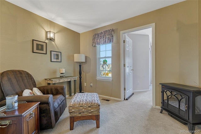 living area featuring a wood stove, light carpet, visible vents, and baseboards