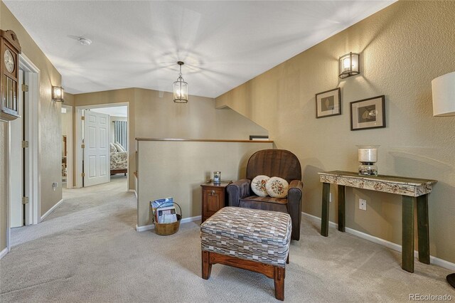 living area with carpet floors, a textured wall, and baseboards