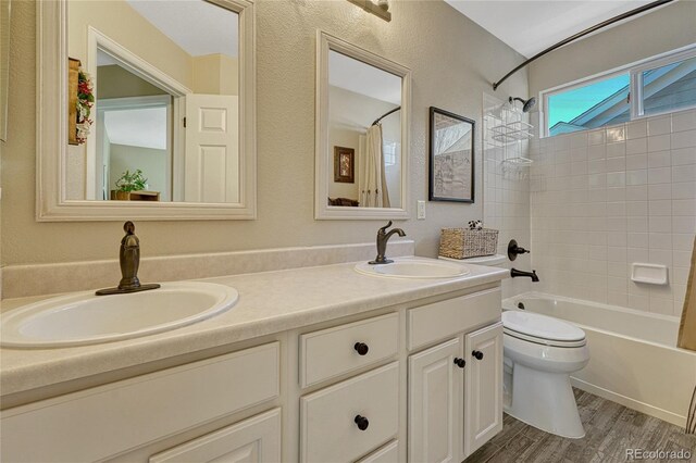 bathroom with wood finished floors, double vanity, shower / tub combo, and a sink