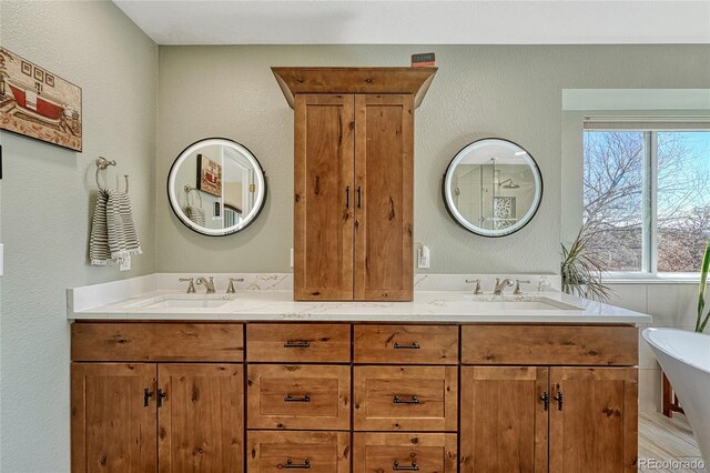 bathroom featuring a freestanding bath, double vanity, and a sink