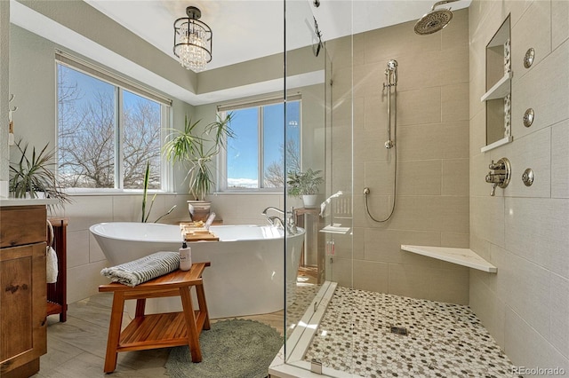 bathroom with a freestanding bath, a stall shower, tile walls, and an inviting chandelier