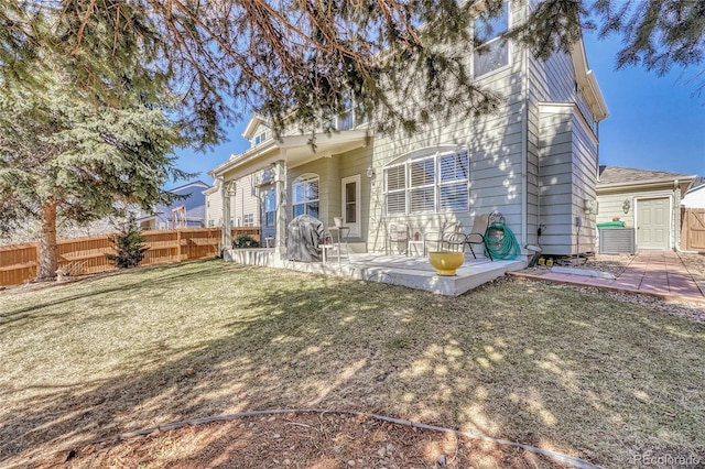 rear view of house featuring a yard, fence, and a patio