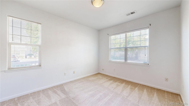 unfurnished room featuring light carpet and baseboards