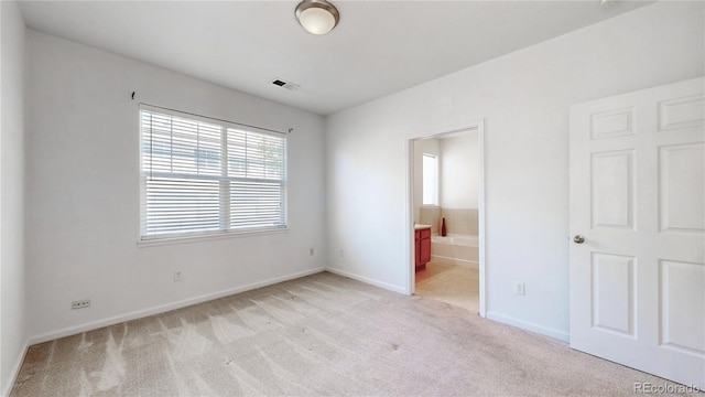 unfurnished bedroom featuring light carpet, baseboards, and connected bathroom
