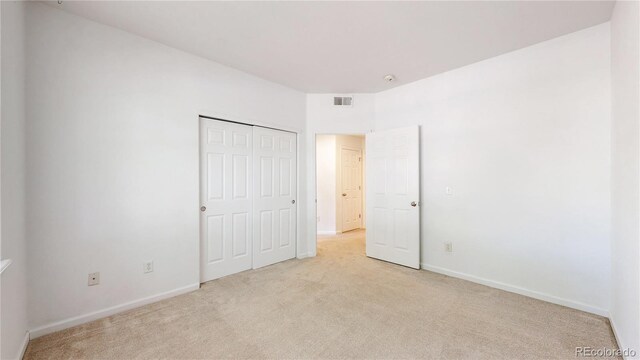 unfurnished bedroom featuring light colored carpet, baseboards, and a closet