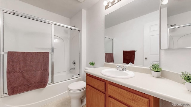 bathroom with combined bath / shower with glass door, toilet, vanity, and tile patterned flooring
