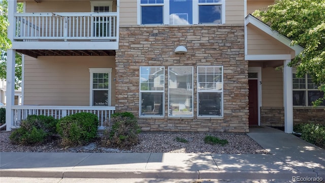 doorway to property featuring stone siding and a balcony