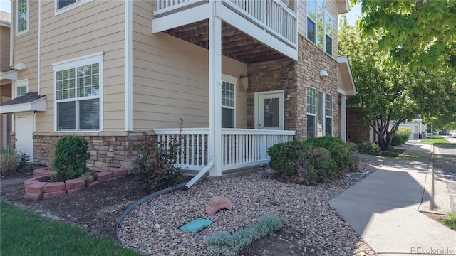 view of side of property with stone siding and covered porch