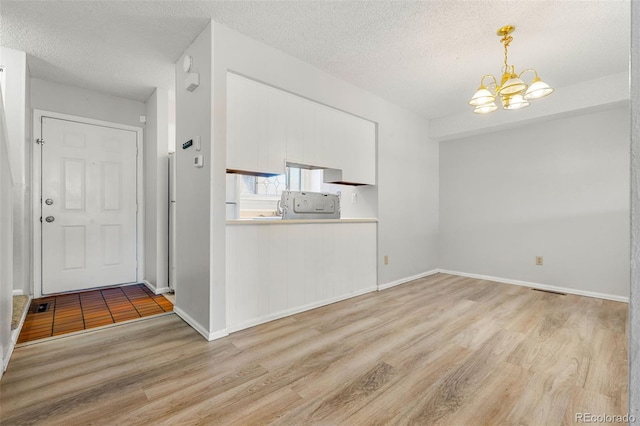 interior space featuring an inviting chandelier, a textured ceiling, and light hardwood / wood-style flooring