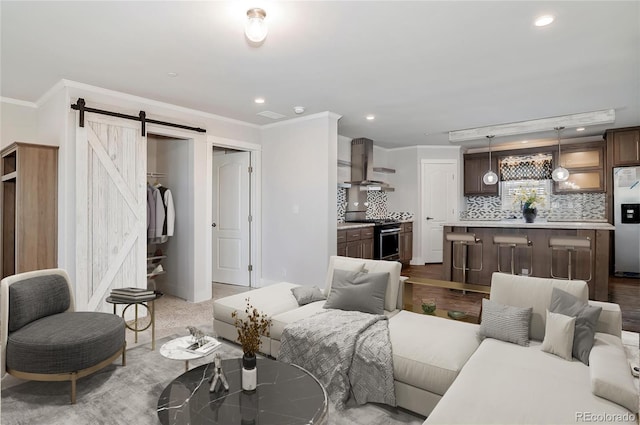 living room featuring light hardwood / wood-style flooring, ornamental molding, and a barn door