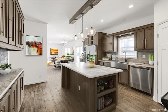 kitchen with appliances with stainless steel finishes, dark brown cabinetry, sink, a center island, and hanging light fixtures