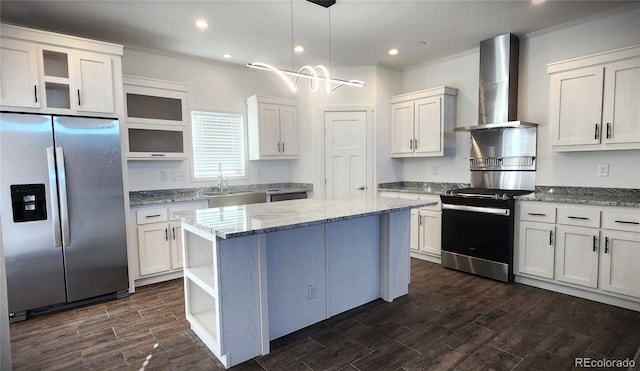 kitchen with sink, wall chimney exhaust hood, pendant lighting, a kitchen island, and appliances with stainless steel finishes