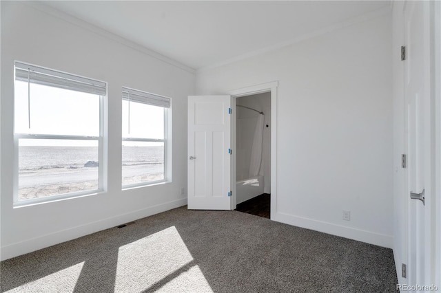 unfurnished bedroom with ornamental molding and dark carpet