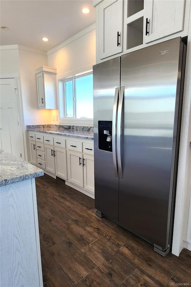 kitchen featuring white cabinets, dark hardwood / wood-style flooring, ornamental molding, stainless steel fridge with ice dispenser, and light stone countertops