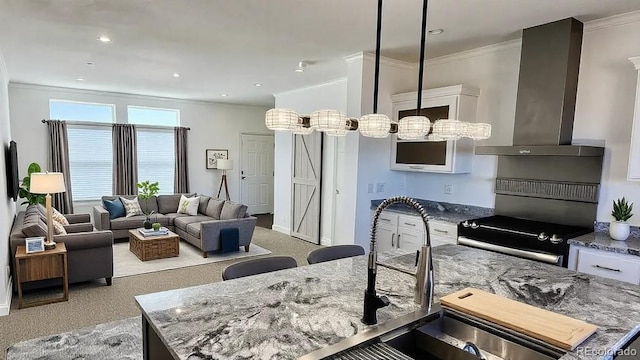 kitchen with wall chimney exhaust hood, stone countertops, a center island, hanging light fixtures, and electric range oven