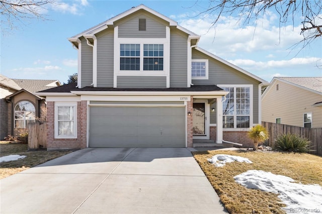 traditional home featuring concrete driveway, brick siding, an attached garage, and fence