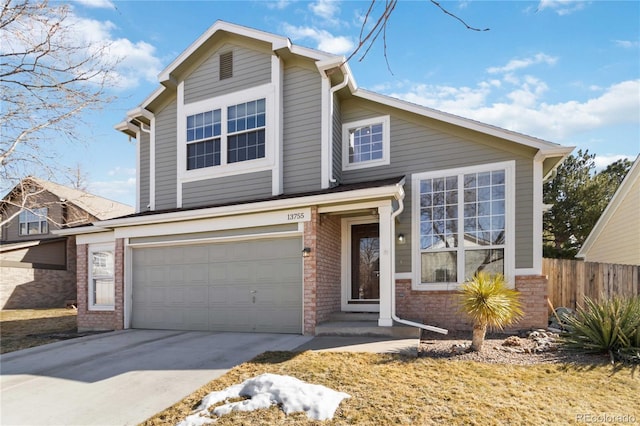 traditional home with a garage, concrete driveway, brick siding, and fence