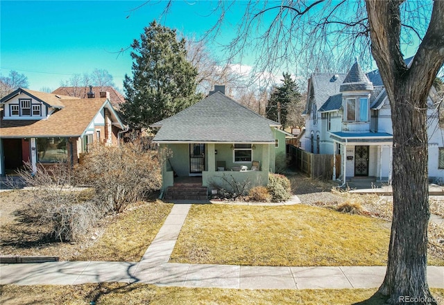 view of front of house featuring a porch, fence, a shingled roof, and a front lawn