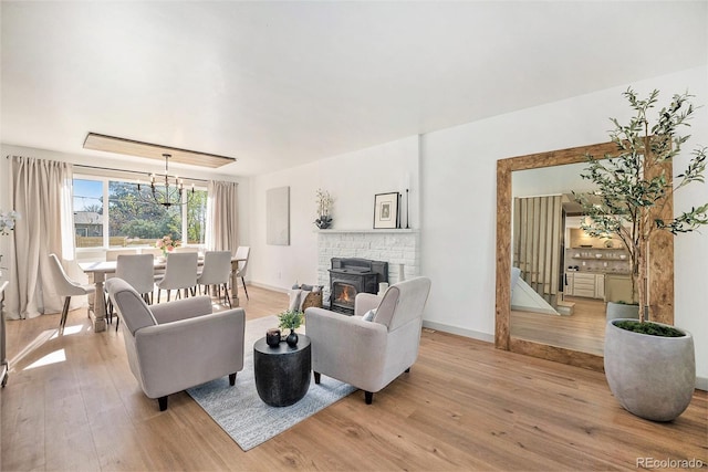 living area with baseboards, a chandelier, and light wood-type flooring