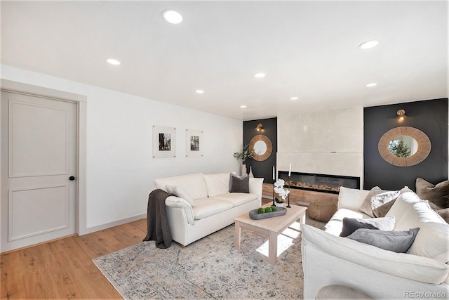 living area featuring baseboards, recessed lighting, a fireplace, and light wood-type flooring